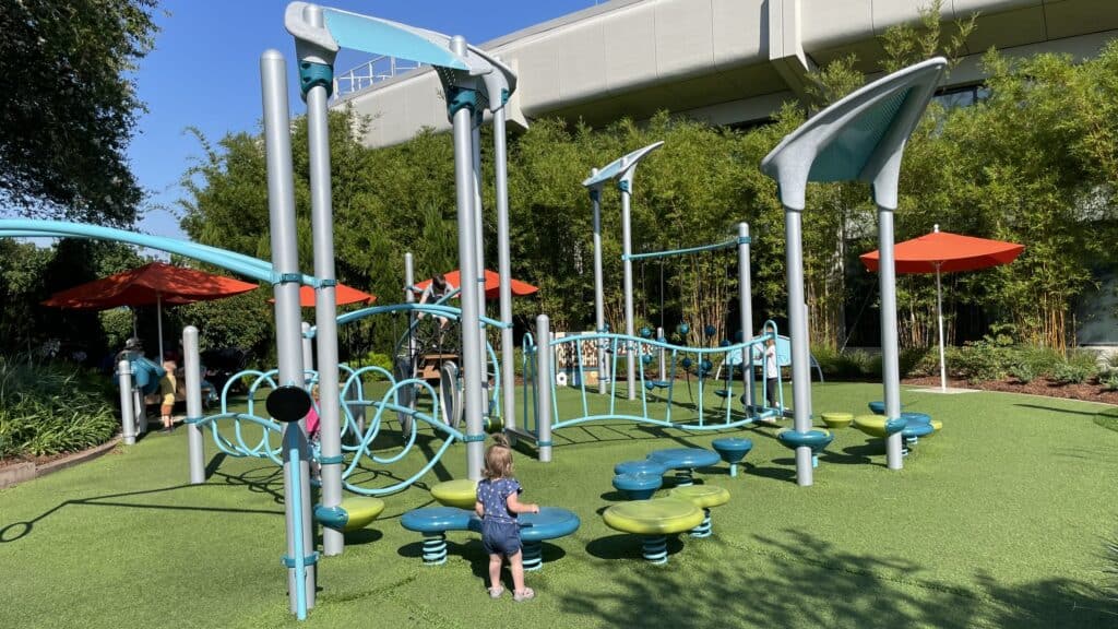 Young child exploring a vibrant playground at EPCOT, featuring colorful climbing structures and play equipment, a delightful stop when traveling to Disney World alone with toddlers.