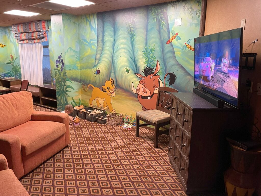Simba’s Cubhouse at Animal Kingdom Lodge with soft seating, toys, and a colorful Lion King mural on the wall.