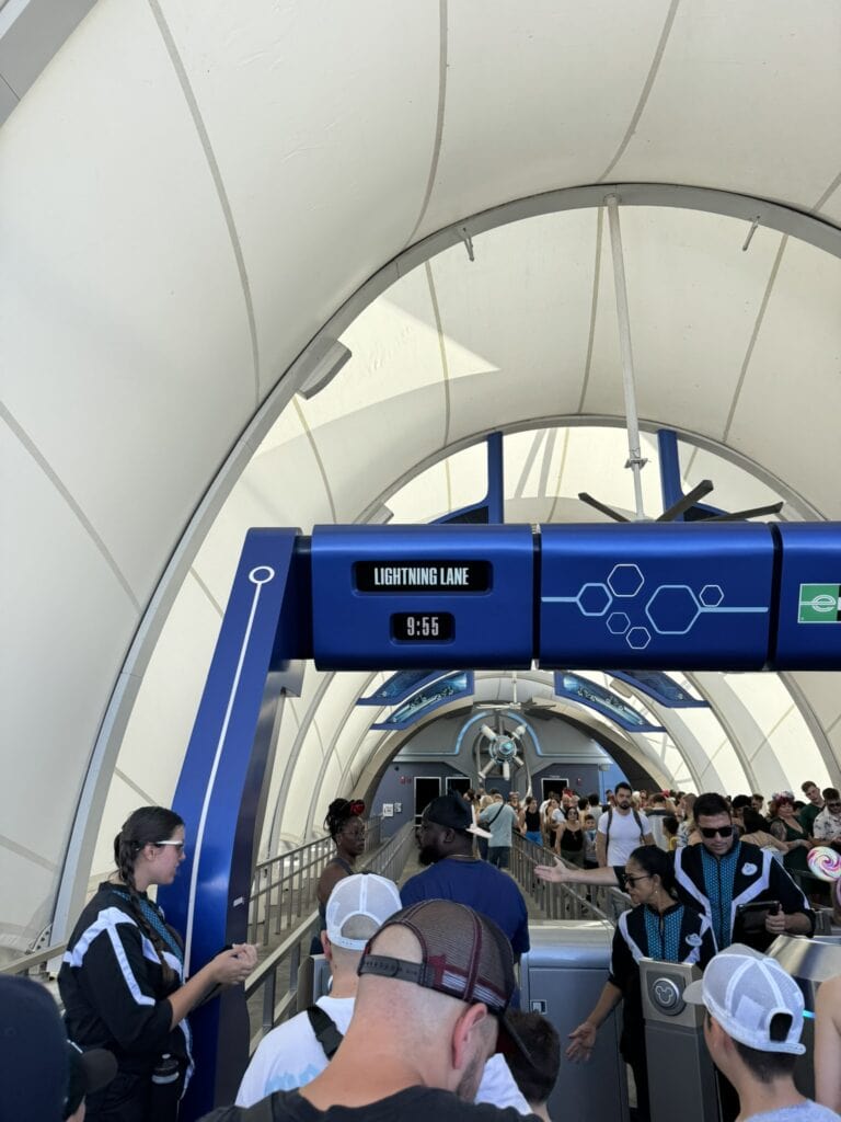 uests enter the Lightning Lane for TRON Lightcycle / Run at Magic Kingdom under a futuristic white canopy, with Disney cast members scanning passes. This shows what’s included when asking Is Disney World Premier Pass worth it with kids.