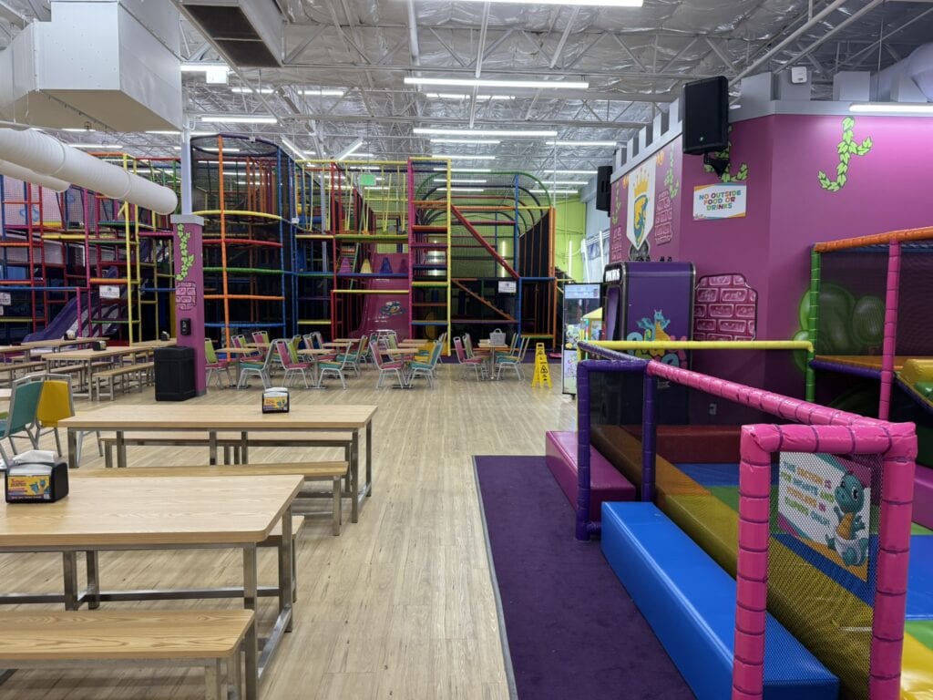 A colorful indoor playground at Kids Empire in Bear, Delaware, with large climbing structures and open tables, perfect for kids to run, climb, and explore.