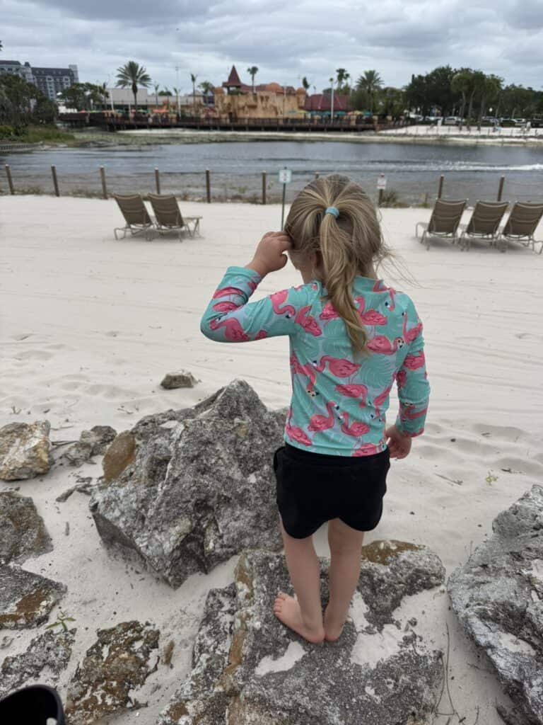 Child standing on the beach at Disney's Caribbean Beach Resort overlooking Barefoot Bay and the pirate-themed splash area.