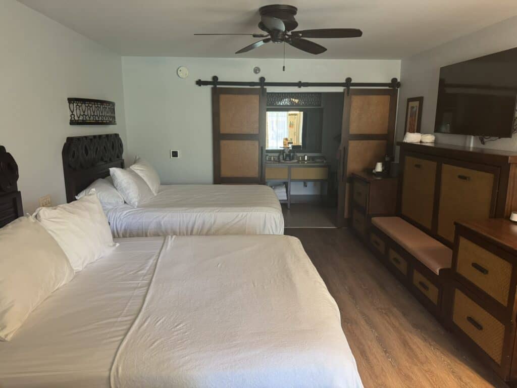 Preferred room at Caribbean Beach Resort with kids, featuring two queen beds, a fifth sleeper, and sliding barn-style bathroom doors.