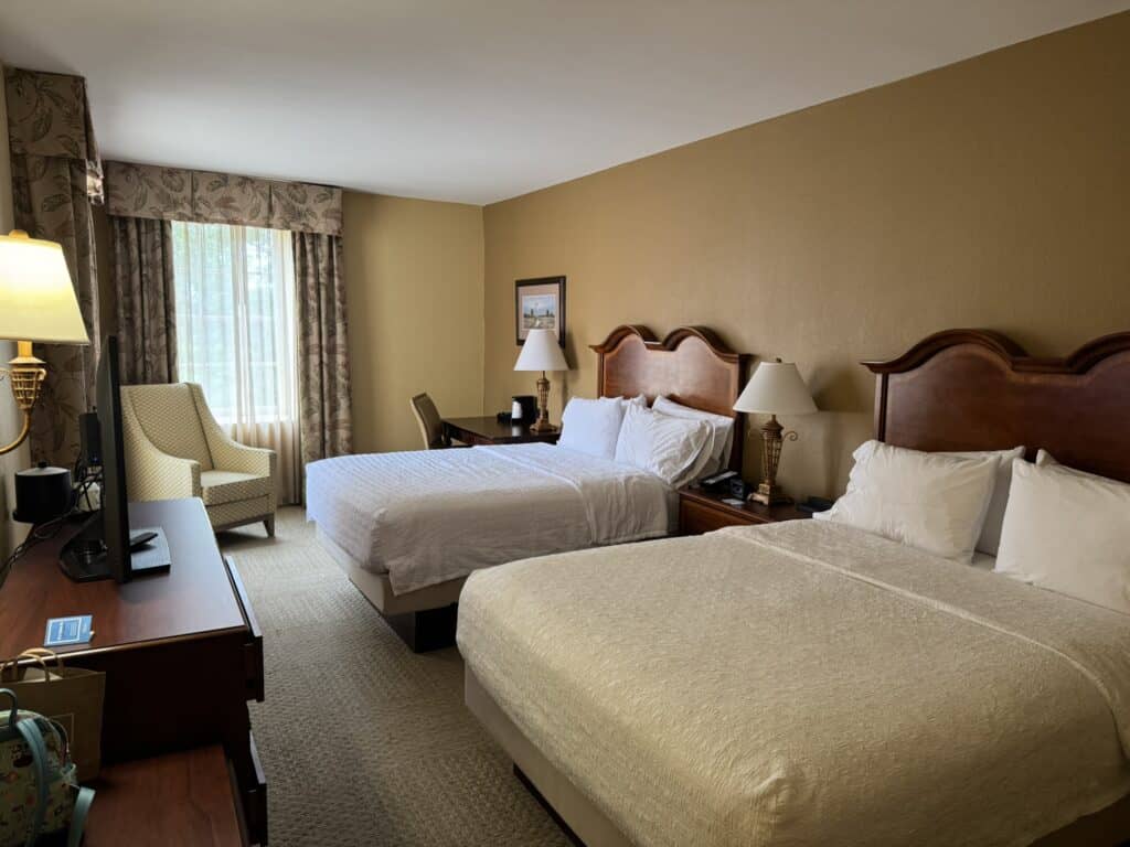 Two queen room at Hampton Inn Charleston-Historic District with kids, including wood headboards, a desk, and a window.