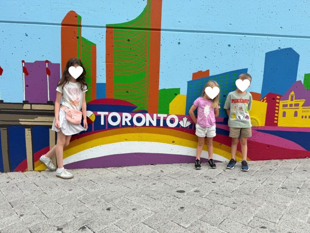 3 kids posing by a Toronto mural during our 2 days in Toronto with kids
