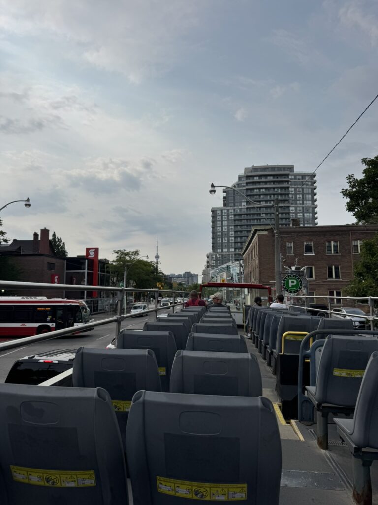 Open top seating on a City Sightseeing Toronto hop-on hop-off bus with the CN Tower in the distance