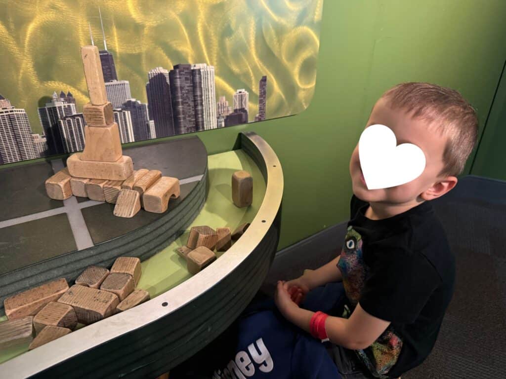 Discovery Place Science with kids building a wooden block skyscraper in Project Build
